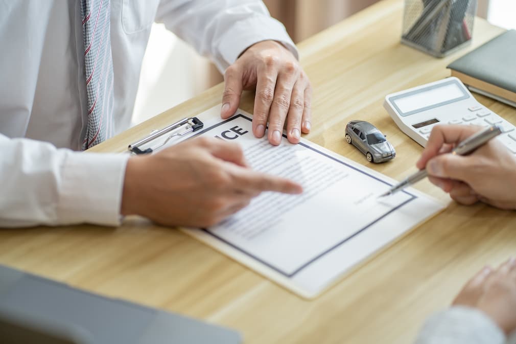 車買取の必要書類を指さすスタッフ
