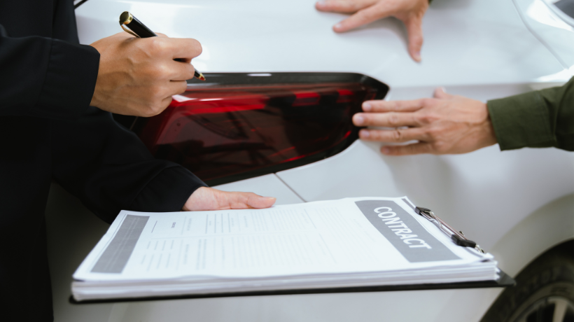 車の売却を検討している人が、車・書類などを見ながら手続きを確認している様子。